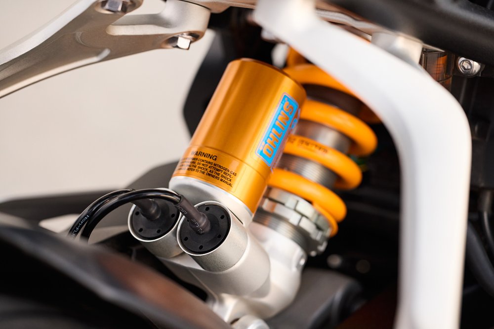 close shot of gold Ohlins shock absorber with wires going into it
