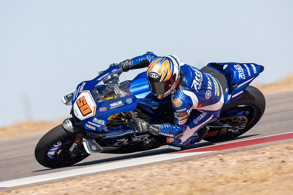 Bobby Fong on a blue Yamaha R1 and wearing blue leathers leaned over in a corner at the preseason test