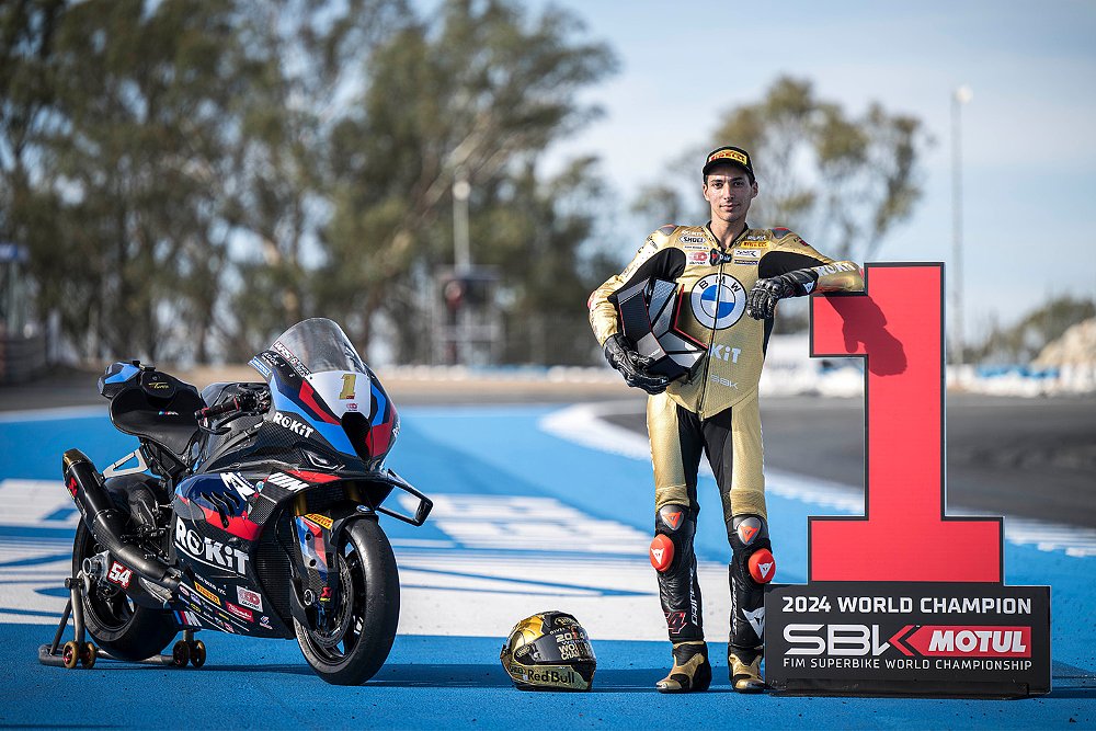 2024 World Superbike Champion Toprak Razgatlioglu standing next to his BMW M 1000 RR factory race bike.