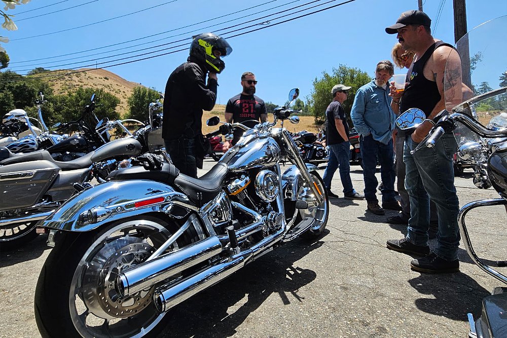 Onlookers gather around the Fat Boy Gray Ghost while Dustin fastens his helmet.