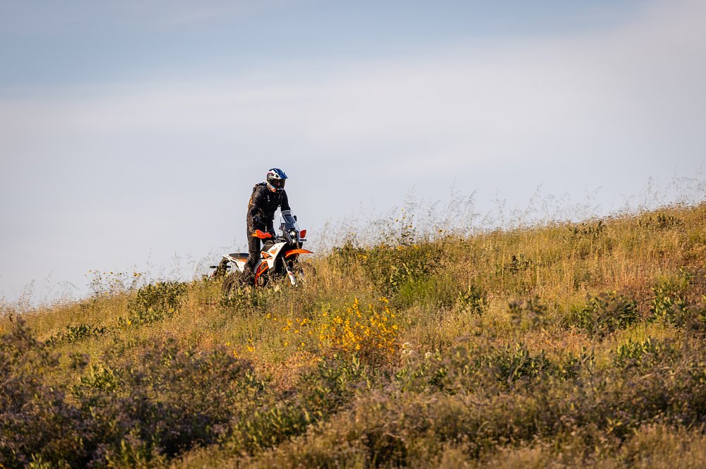 2025 KTM 390 Adventure R riding through a field with the rider standing up.