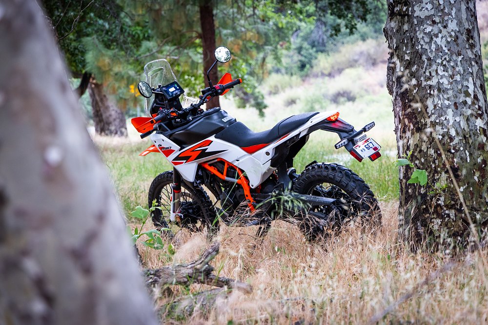 2025 KTM 390 Adventure R left-rear three quarter, seen parked amongst trees.
