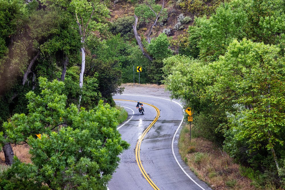 2025 KTM 390 Adventure R riding on a wet mountain road.