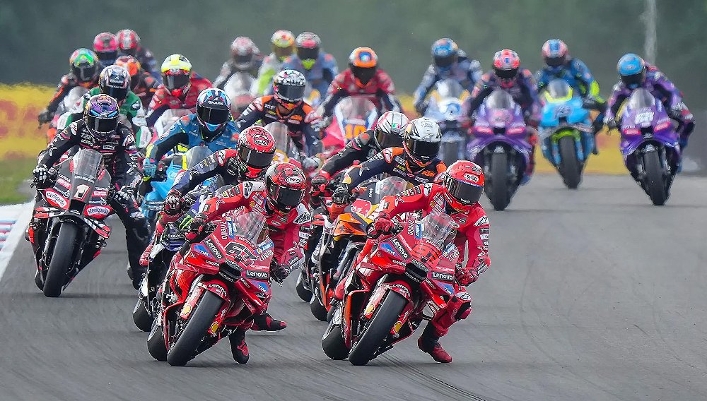 Marc Marquez and Pecco Bagnaia lead a pack of MotoGP riders into a turn.