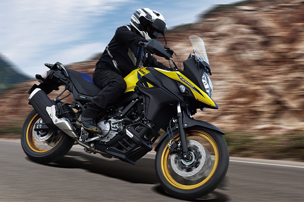 A V-Strom 650 rider leans around a corner on a mountain road.