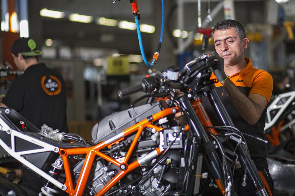 Several employees assemble motorcycles in a KTM factory.