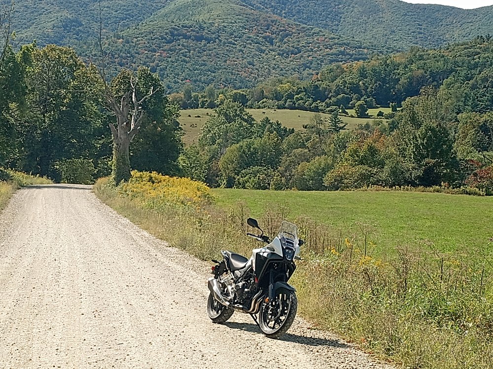 NX500 parked on a country dirt road with mountains and meadows in the distance