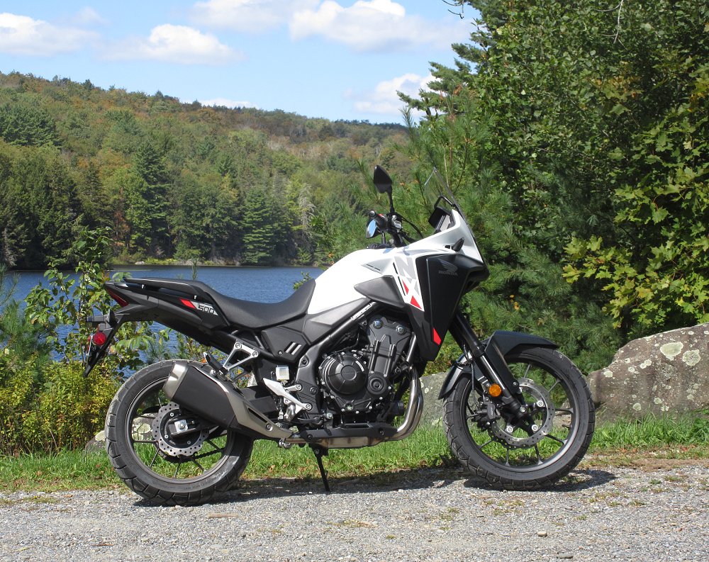 side view of the white NX500 parked by a blue country lake