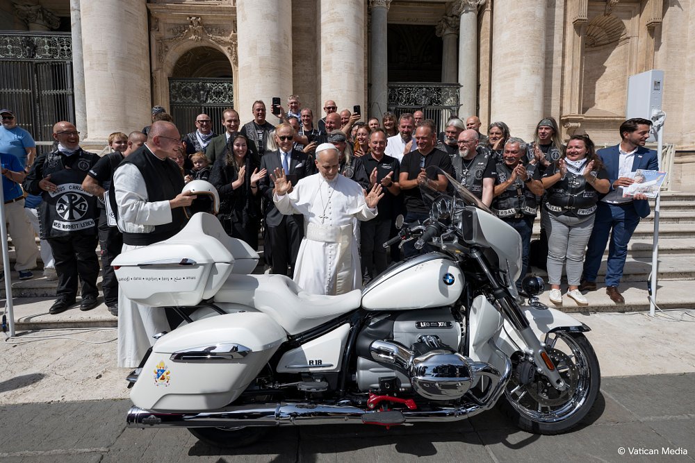 Pope Leo XIV with a white BMW R 18 Transcontinental, surrounded by other people.