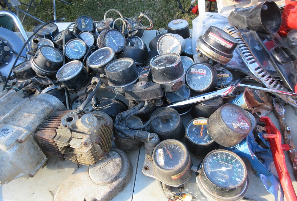 a pile of dusty old motorcycle speedometers