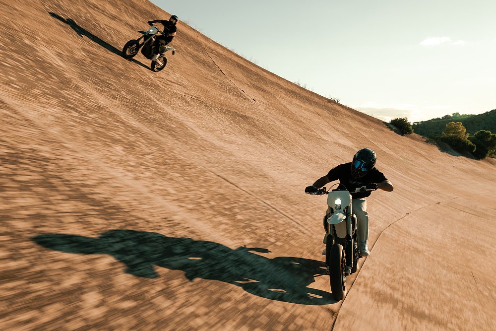 A pair of Stark VARG SM riders speed up the banked walls of a race track.