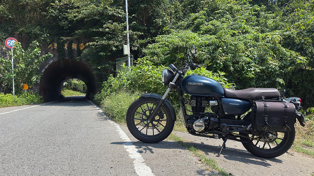 A Honda GB350 parked roadside with a tunnel in the background.