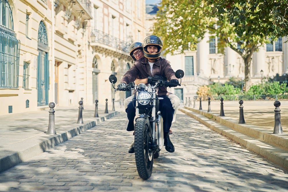 A couple rides the RM2 down a cobblestone road somewhere in Europe.